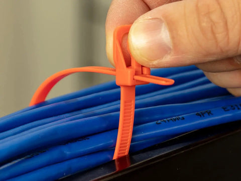 Person using Heavy Duty Reusable Cable Ties With No Sweat Quick Release Lever on blue cables for secure wiring control.