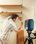 Green Beam Self-Leveling Cross-Line Laser Kit With 40 Ft Range used for precise shelf installation on a job site.
