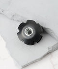 Close-up of black Two Pack Bicycle Front Fork Bowl Star Nuts for 1 1/4 inch diameter forks with M6 threads, on white surface