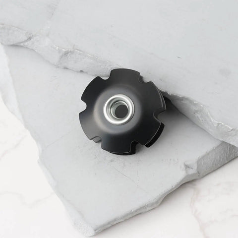 Close-up of black Two Pack Bicycle Front Fork Bowl Star Nuts for 1 1/4 inch diameter forks with M6 threads, on white surface