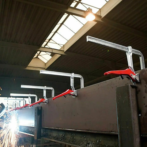 Heavy Duty Ratchet Lever Clamps 12 Inch Fast Action Welding And Woodworking Tools lined up on a workbench in a workshop.
