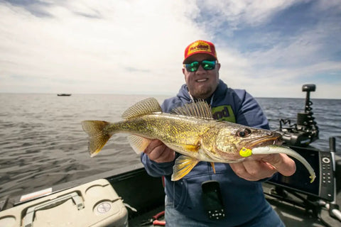 Angler holding fish caught with Elite Series MVP Jig With Premium Hook And Gamakatsu Big River Hook For Walleye Bass And Trout Assorted Colors Quarter Ounce Jig Head Designed For Deep Penetration And Heavy Hitters on a boat.