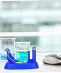Sky-blue brass pendulum kit for classroom science, shown near beakers, a hands-on physics lab tool in middle school setup.