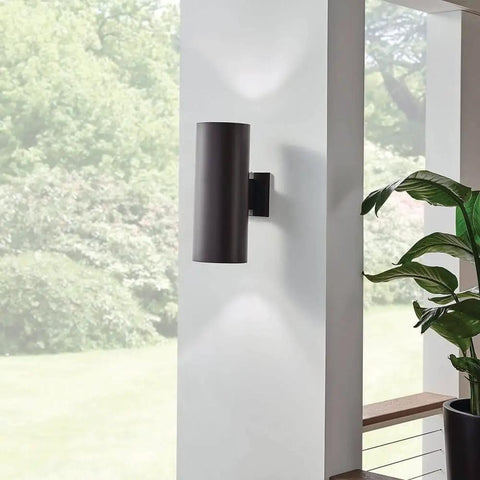 Outdoor Cylinder Wall Sconce In Architectural Bronze Two Light 15 Inch Tall 6 Inch Wide Weatherproof Porch Lighting With E26 Socket For BR40 Bulbs Bulbs Not Included, mounted on a modern white wall, casting up/down light.