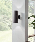 Outdoor Cylinder Wall Mount Sconce With Up And Down Lighting In White Finish by door, showing light distribution, garden view