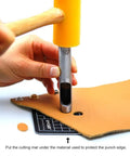 Using 12 Piece Leather Hole Punch Set With Free Cutting Mat on leather with a hammer, showing ergonomic non-slip handles.