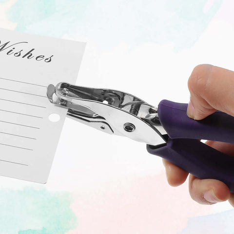 Hand using 16 Pack Handheld Hole Puncher With Soft Grip 1/4 Inch Circle Punch on greeting card, featuring purple grip