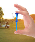 Hand holding Unbreakable Three And A Quarter Inch Plastic Golf Tee in blue against golf course backdrop