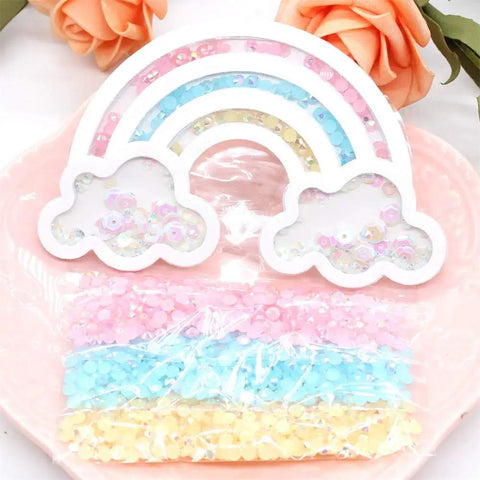 Rainbow Shaker Bag Topper Die Set For DIY Scrapbooking And Photo Albums, with colorful sequins inside cloud shapes on pink plate.
