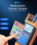 Front view of Komshine KLT-12E optical fiber tester, orange handheld unit with display and blue fiber cable