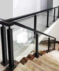 Modern glass railing with black metal supports along a staircase, combining safety and style in an indoor setting.