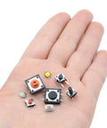 Hand holding various micro momentary tactile push button switches from 240 Piece Micro Momentary Tactile Push Button Switches Assortment Kit