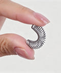 Super Cool TopHomer 300 Pack Compression Springs Made From Solid Stainless Steel With Diverse Hook Configurations Perfect For DIY Repairs And Tough Machine Fixes To Keep Everything Moving Smooth Without Any Hiccups. close-up stainless steel compression spring held between fingers