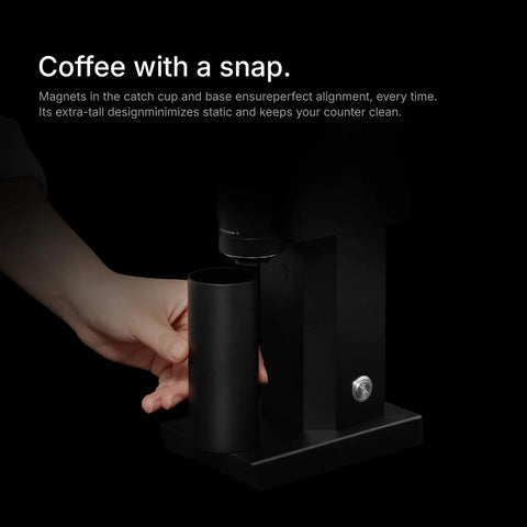Hand holding container near Badass Electric Coffee Grinder With 150 Tight Adjustments, Slick Stainless Steel Housing, And Knockout Uniform Grind For Espresso Pour Over And French Press In Matte Black.
