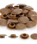 Twenty Piece Light Oak Door Threshold Screw Covers in a pile, 3/8 inch plastic caps for concealing fasteners.