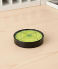 Qianly Bubble Level with Degree Markings Metal Circular Spirit Level Compact for Home Improvement Hobbyists, Turntable Alignment, Black Shell, Green Liquid, 60x12mm placed on wooden surface.