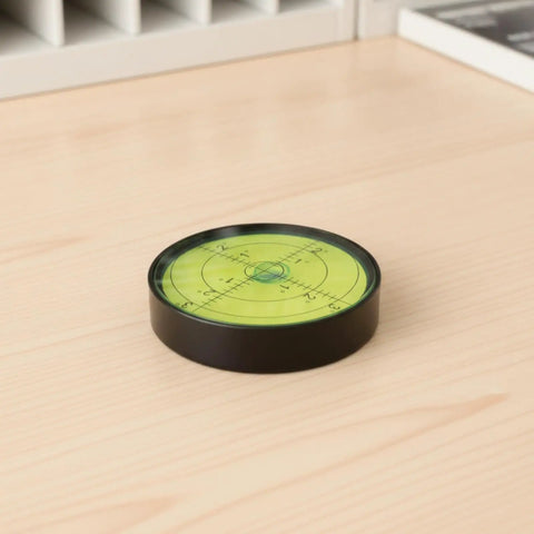 Qianly Bubble Level with Degree Markings Metal Circular Spirit Level Compact for Home Improvement Hobbyists, Turntable Alignment, Black Shell, Green Liquid, 60x12mm placed on wooden surface.