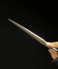 Person holding Kunai Inspired Throwing Tool With Full Tang Stainless Steel Build against dark background.