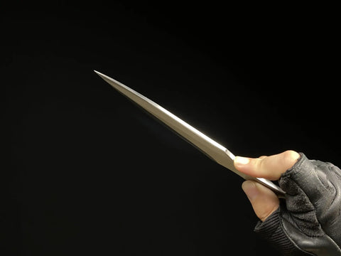 Person holding Kunai Inspired Throwing Tool With Full Tang Stainless Steel Build against dark background.