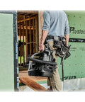 Person carrying Beast Series 5 Gallon Wet Dry Vacuum With 5.5 HP Motor, entering construction site, focus on portability and design