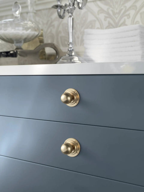 Close-up of Champagne Bronze Cabinet Knobs With Backplate Set Of 6 on a blue cabinet, showcasing vintage style drawer pulls.