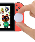 Hand holding a 50 Pack White NFC Tags NTAG215 Coins with Adhesive Back near gaming console, 25mm coin size