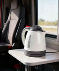 Heavy Duty 24V Electric Kettle For Trucks Built Like A Tank With Auto Shut Off 1 Liter Portable Water Heater on a table in a truck cabin.