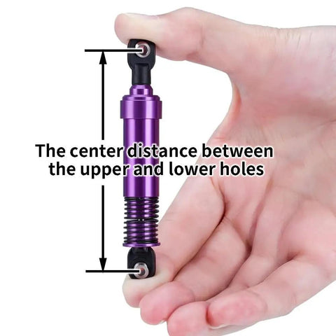Hand holding RC Crawler Shocks 75mm-115mm Bore for 1/10 Scale Builds, highlighting center distance measurement, purple metal, black ends.