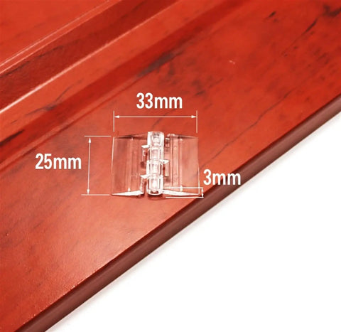 Close-up of a clear acrylic 25x33mm hinge on wood. Pack Of 10 Transparent Plastic Folding Hinges In 25x33 30x33 38x45 And 65x42 Sizes Built To Last Transparent Clear Acrylic Hinges For DIY Projects Cabinets Boxes And Craft Builds.