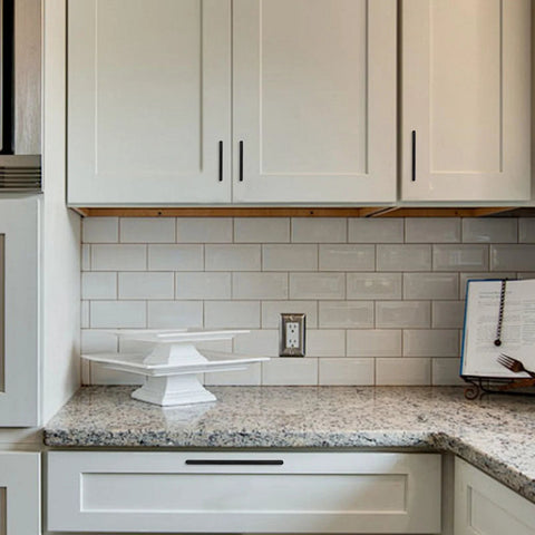 Matte black zinc alloy cabinet pulls installed on white kitchen cabinets showing 5 inch solid hardware in modern style.