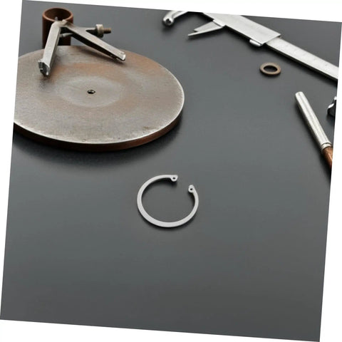 Stainless Steel C Clip from 5 Pack with Grooved Retaining Rings on dark surface, tools in background