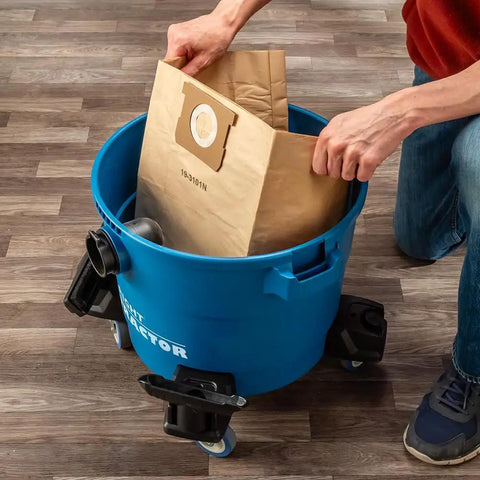 Person inserting a filter bag into a blue 9 Gallon HEPA Dust Collector Auto Starts With Your Power Tools.