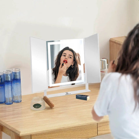 Vanity Tri Fold Makeup Mirror With 3 Lighting Modes Dimmable Smart Touch Control in use on tabletop with woman applying makeup.