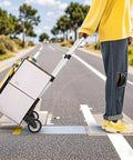 Person using folding telescoping hand truck on road, transporting items.