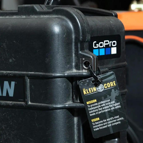 Black GoPro case with Klein Core tag showing mission and vision statements in workshop setting.