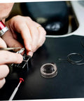 Person using tools from Complete Mechanical Alarm Clock Repair Kit With Spring Steel Return Spring Assembly for clock maintenance