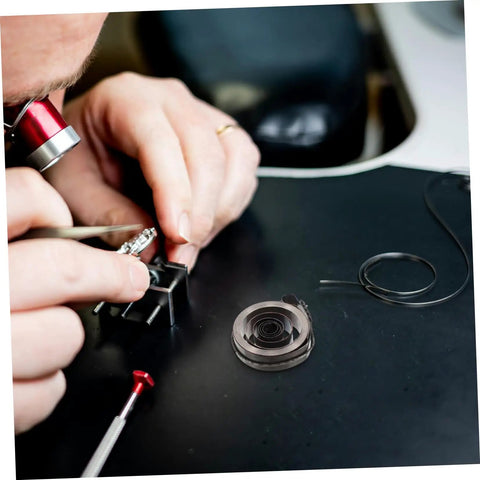 Person using tools from Complete Mechanical Alarm Clock Repair Kit With Spring Steel Return Spring Assembly for clock maintenance