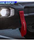 Custom Red Deco Tow Strap For Car Bumper And Trunk, Stylish Trailer Belt Plus Towing Rope Auto Exterior Bling With Abs Hook, Personalized Racing Stripe Decor That Gives Your Whip Serious Street Cred mounted on a car bumper at night.