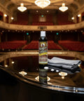 Top Shelf Wood Polish And Gloss Restorer to Wipe Away Scratches Haze and Dust on a grand piano with a cleaning cloth.