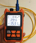 Orange handheld optical fiber power meter with yellow fiber lead, 1310 nm readout on screen, front view
