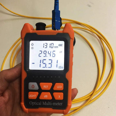 Orange handheld optical fiber power meter with yellow fiber lead, 1310 nm readout on screen, front view