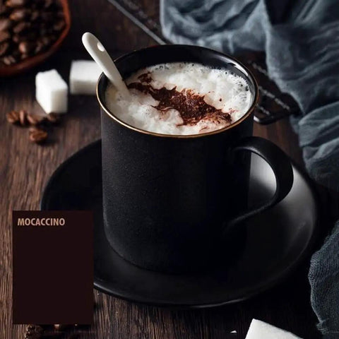 Cup of mocaccino with foam and chocolate on top on a saucer, sugar cubes, and coffee beans on a wooden table.