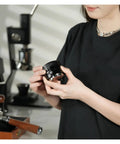 Pro Level Espresso Coffee Distributor And Tamper Set 58.35mm in hand, showcasing gravity adaptive black stainless steel design.