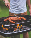 Person grilling sausages over charcoal using Three Pack Fire Starter For Camping And Emergency Prep, Waterproof Pouches.