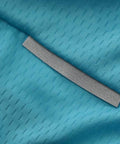 Close-up of teal fabric with diagonal textured pattern and silver reflective strip