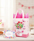 Mother's Day Gift Bags With Tissue Paper Floral Non-Woven Design 10x8x4.7 Inches Pink with card on table.