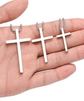 Hand holding Dope Silver Stainless Steel Cross Necklace for Men with 20 Inch Box Chain Pendant, hypoallergenic and lead free.