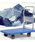 Heavy Duty Foldable Rolling Dolly, No Sweat Hauling With Silent Wheels, Space Saving Steel Frame Pushcart For Quick Home Moves And Warehouse Jobs, Solid Blue Build on snowy terrain.