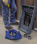 Person in jeans and boots working with electrical panel and blue tool pouch from Large 16-Inch Canvas Tool Pouches 3-Pack with Brass Zippers and Hanging Grommets for Easy Tool Storage, Durable No 8 Canvas, Wide Bottom for Standing, Color Set in Red Yellow Blue.