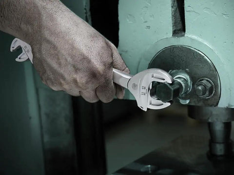 Hand using Joker 6006 Self-Setting Double Spanner With Auto-Grip For Metric And Imperial Fasteners on machinery bolt